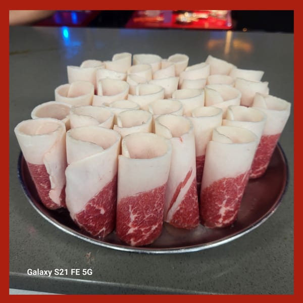 Platter of thinly sliced, rolled Korean BBQ beef, marbled with fat, ready for grilling.